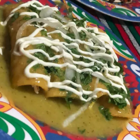 Enchiladas bañadas en salsa con crema y quesito