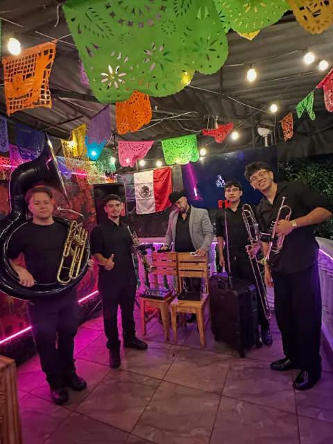 Banda en vivo bajo el papel picado de El Pinche Cabrón