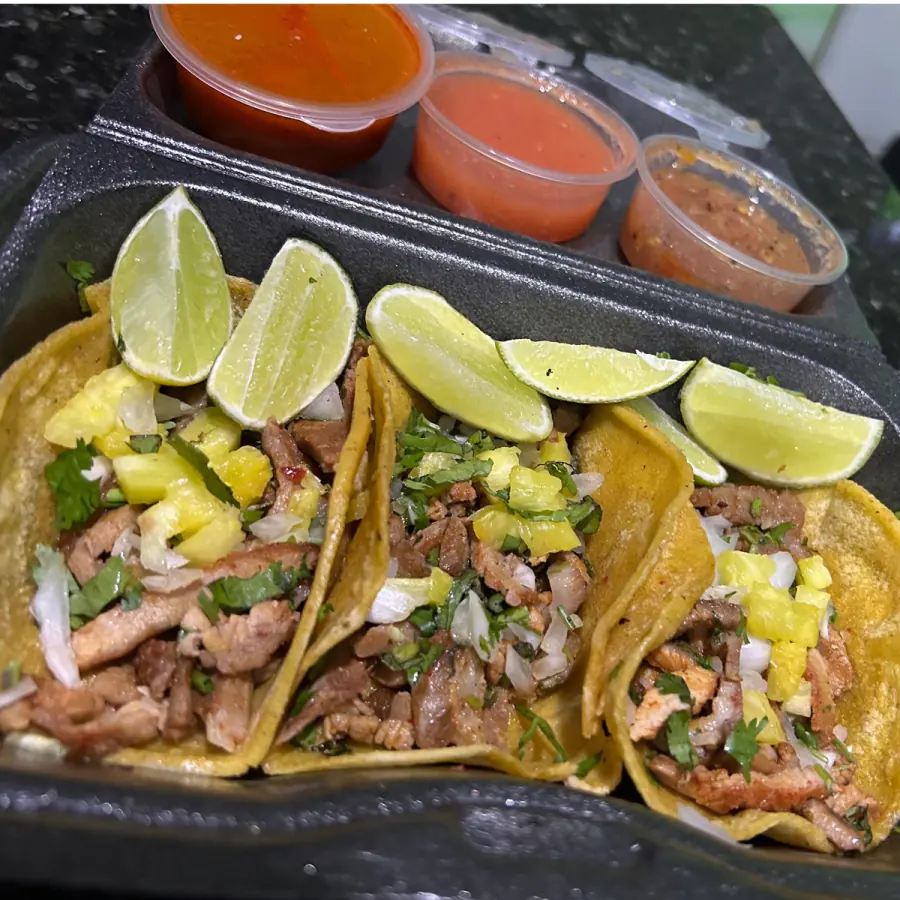 Tacos de pastor con piña, cebolla y cilantro, con salsas y limones